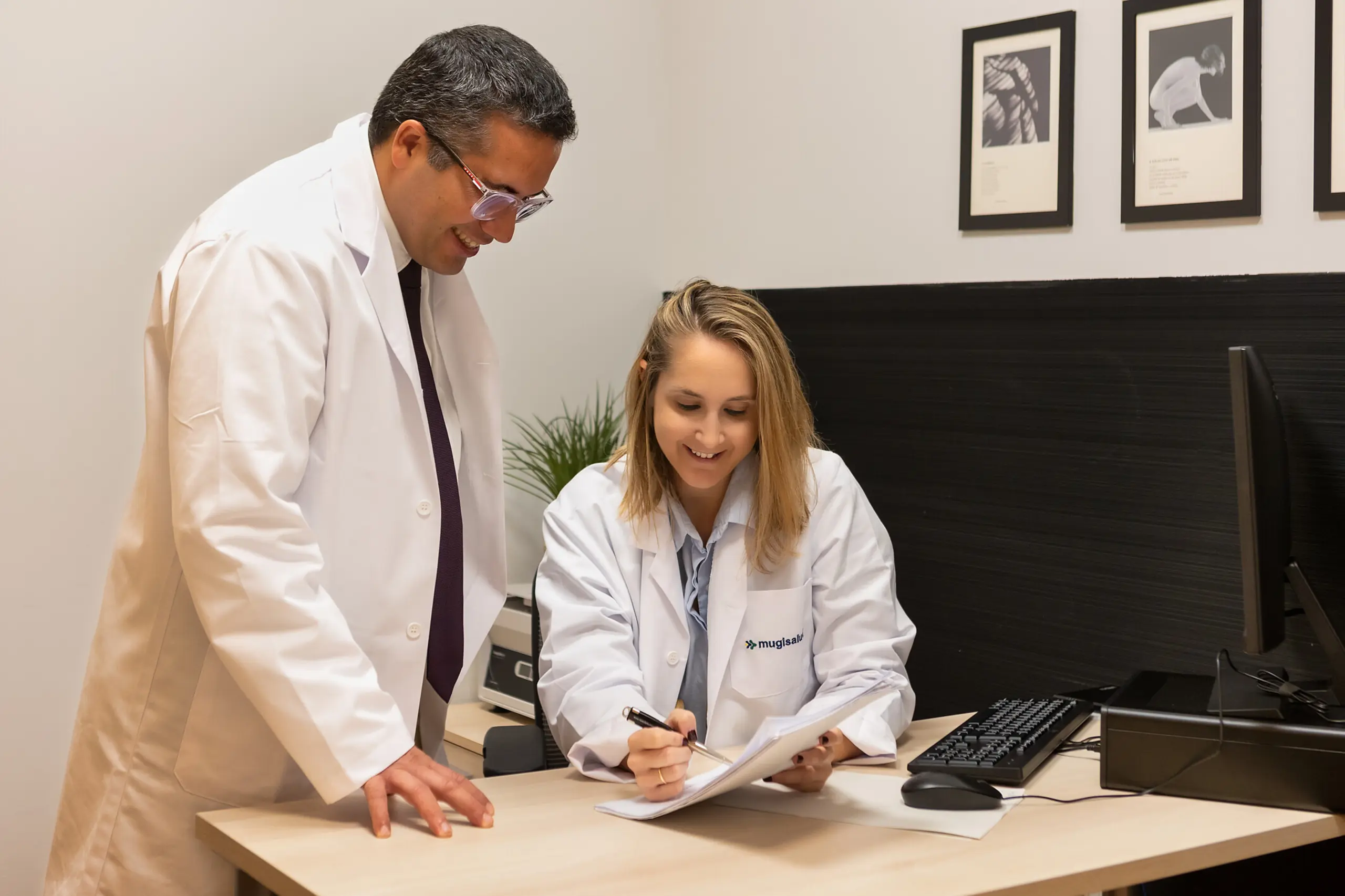 Dos profesionales con bata de Mugisalud revisando un documento en la consulta