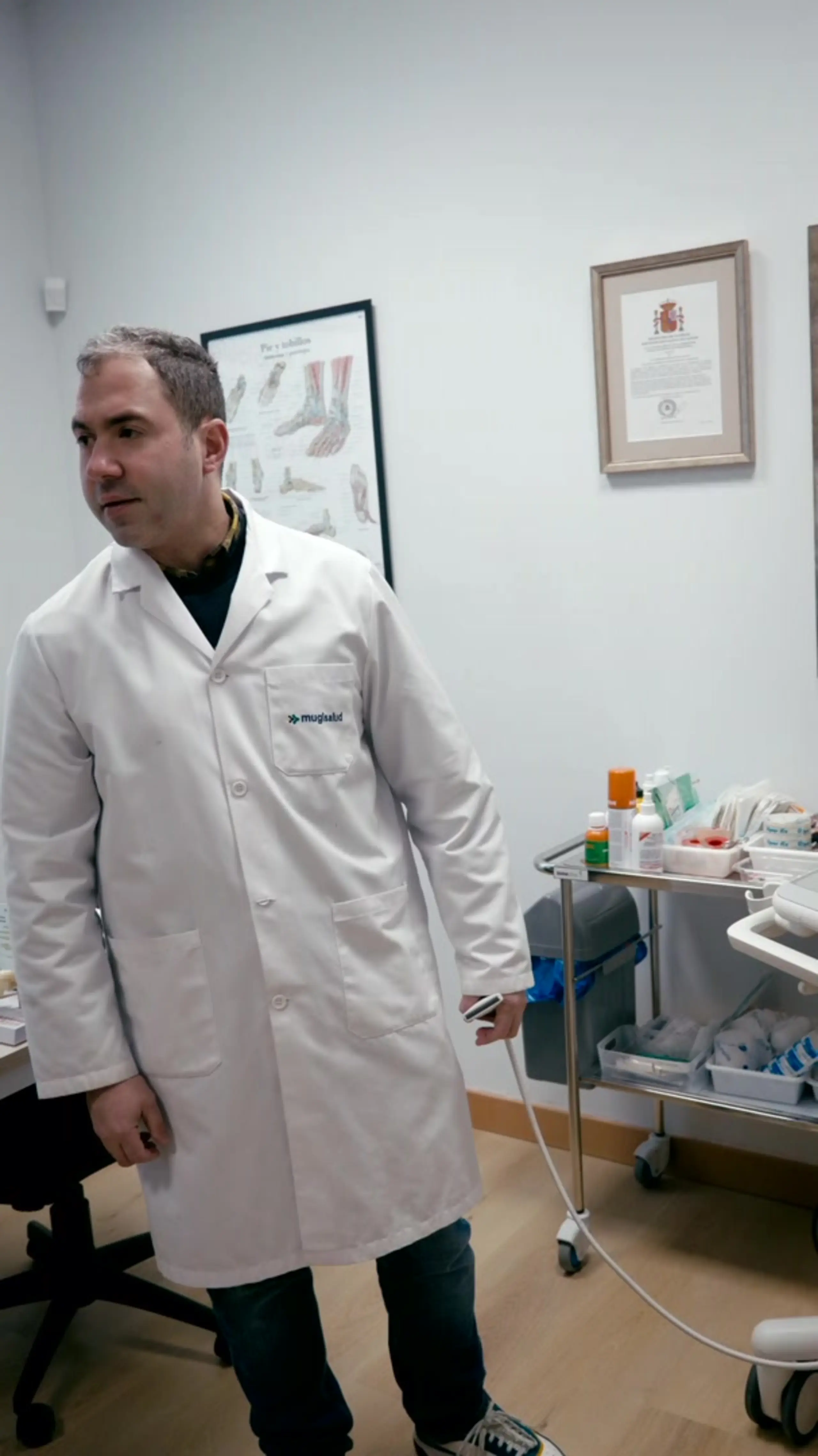 Médico con bata de Mugisalud sosteniendo la sonda del ecógrafo en la consulta